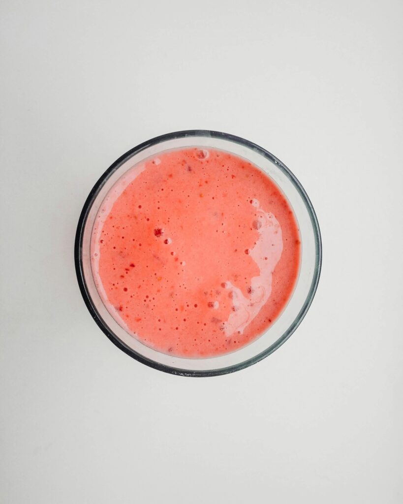 Top view of a vibrant pink strawberry smoothie in a glass, perfect for a refreshing drink.